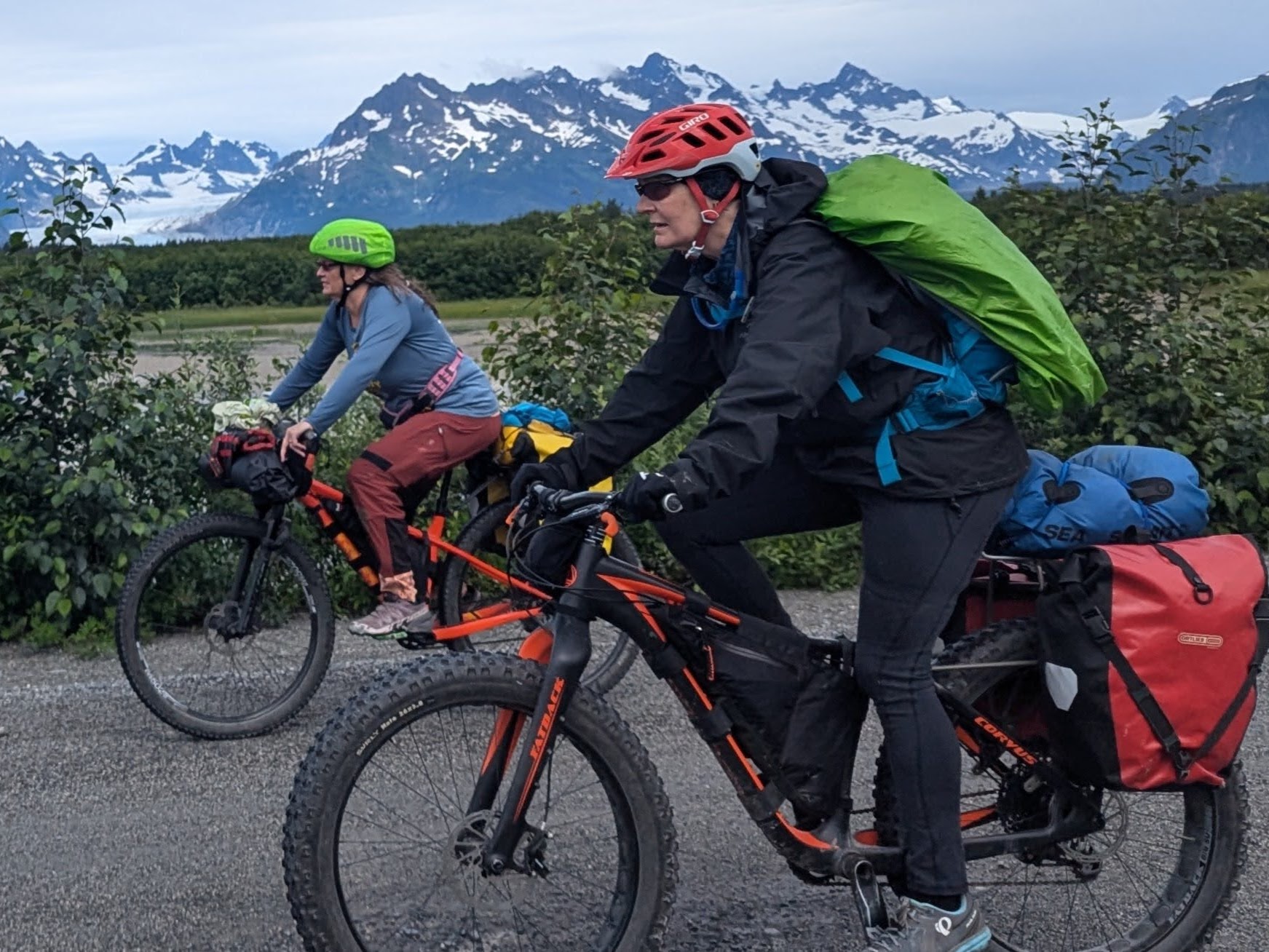 two women bikepacking infront of a mountain range in Alaska